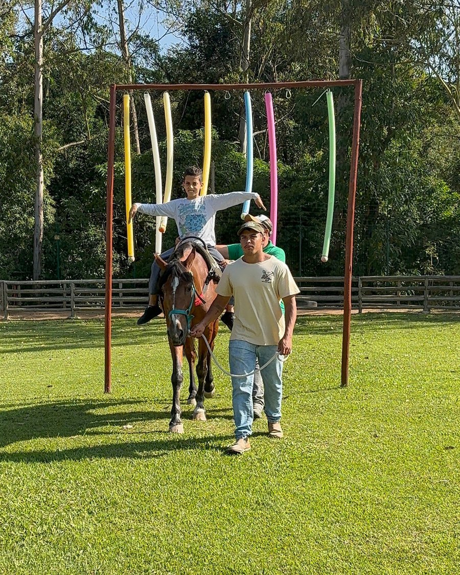 Sessão de equoterapia na Hippus Aldeia, com criança montada e profissionais conduzindo o cavalo