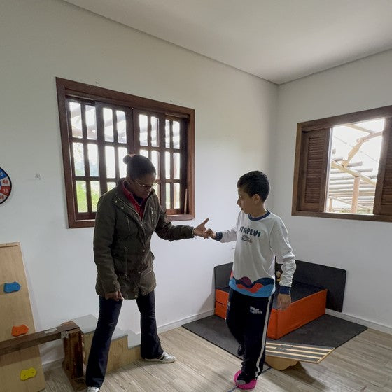 Atividade de educação física na Hippus Aldeia: terapeuta e criança em circuito de equilíbrio